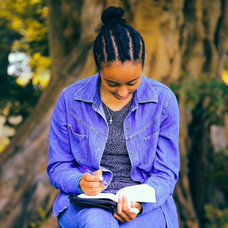 Girl in the park A girl is writing in a notebook in the park